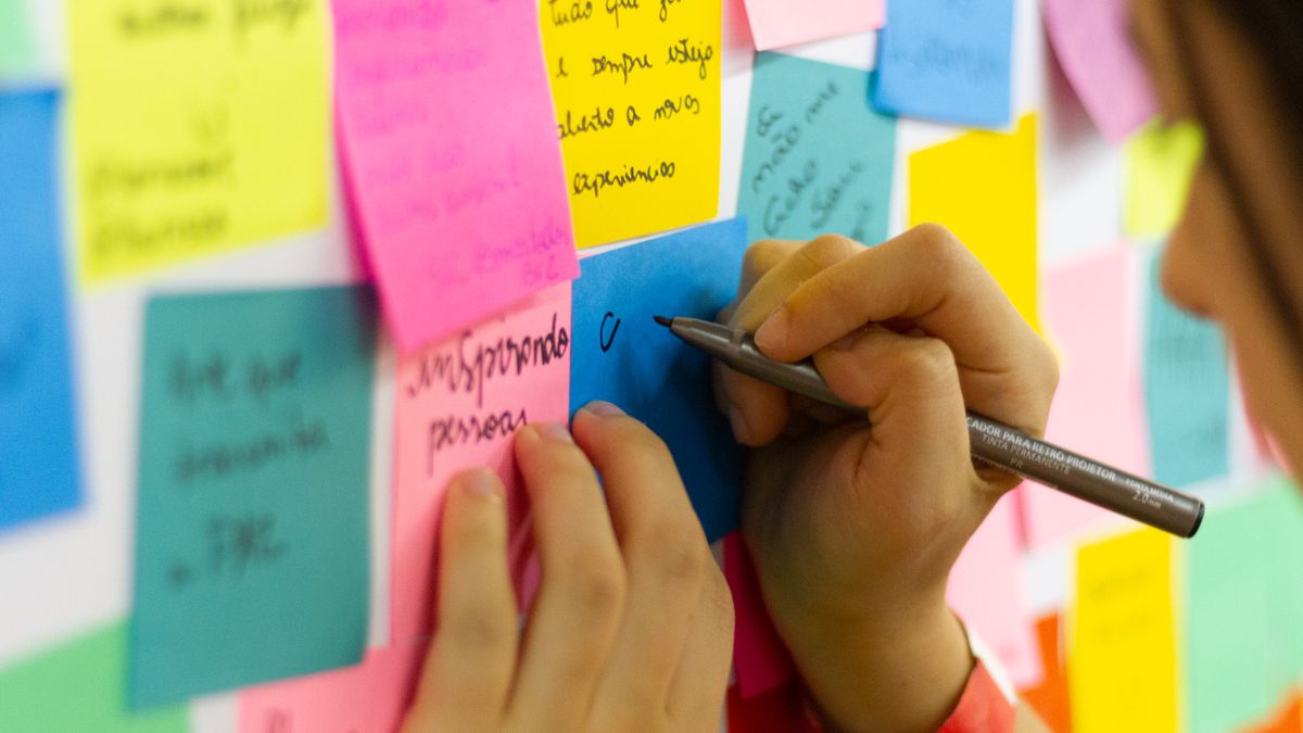 A person writing thoughts onto colourful sticky notes during a brainstorming session