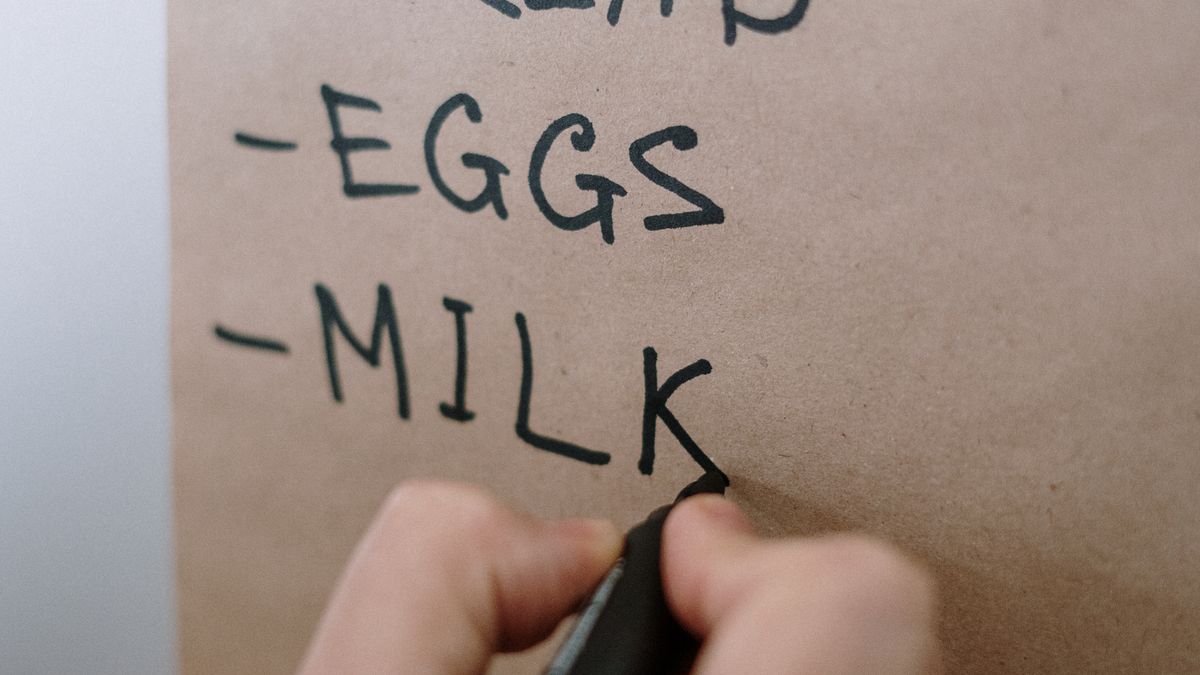 Close-up of a hand writing a shopping list on brown paper with a marker