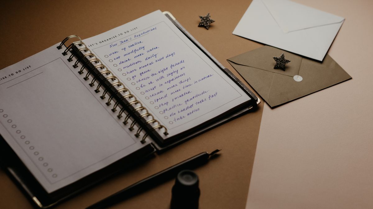 A tidy desk with a paper planner, a handwritten to-do list, envelopes, and a pen